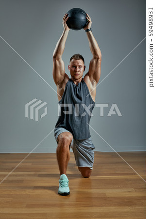 Strong man doing exercise with med ball. Photo of man perfect physique on grey background. Strength 59498931