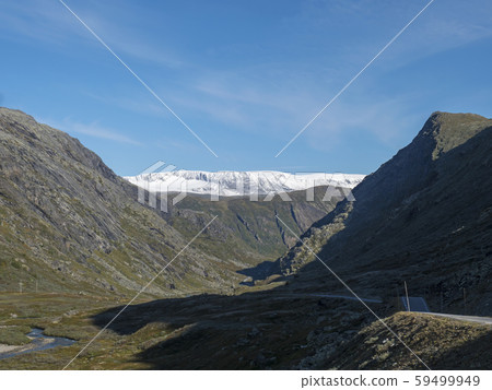 Leirdalen Valley with snow capped mountain peaks, forests, wild river stream and road 55 scenic 59499949