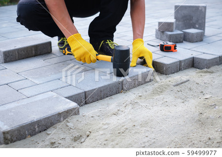 The master in yellow gloves lays paving stones 59499977