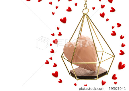 A small red heart flying around a pink heart in a gold basket A small red heart flying around a pink heart in a gold basket 59505941