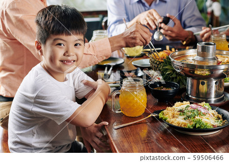 Smiling boy at dinner with relatives 59506466