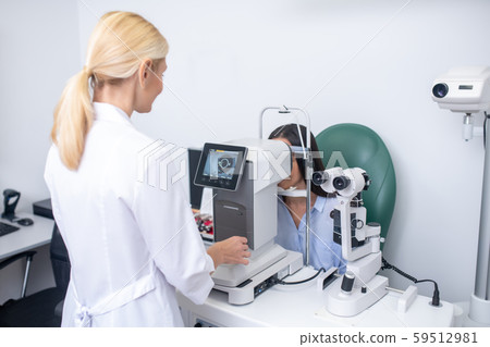 Close up of ophthalmologist using modern equipment while examining patient Close up of ophthalmologist using modern equipment while examining patient 59512981
