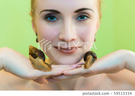 Facial massage a snail Achatina. Snail cleanses the skin of the face of a young woman. Facial massage a snail Achatina. Snail cleanses the skin of the face of a young woman. 59513334