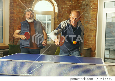 Senior men playing table tennis in workplace, having fun Senior men playing table tennis in workplace, having fun 59515359