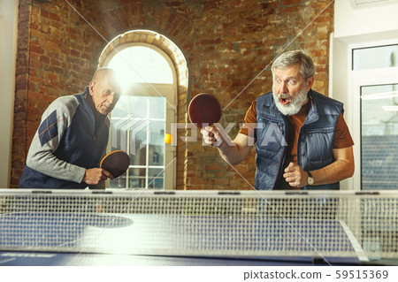 Senior men playing table tennis in workplace, having fun Senior men playing table tennis in workplace, having fun 59515369