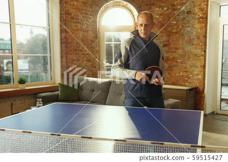 Senior man playing table tennis in workplace, having fun Senior man playing table tennis in workplace, having fun 59515427