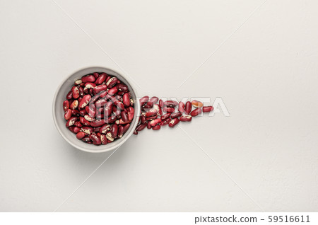 Bowl with red beans on a light textured background. Next to the grain is poured in the form of an 59516611