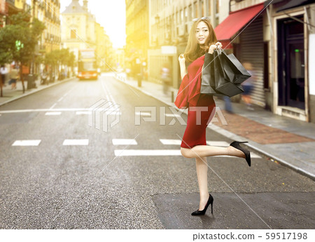 Asian woman in red clothes and sunglasses carrying black shopping bags Asian woman in red clothes and sunglasses carrying black shopping bags 59517198