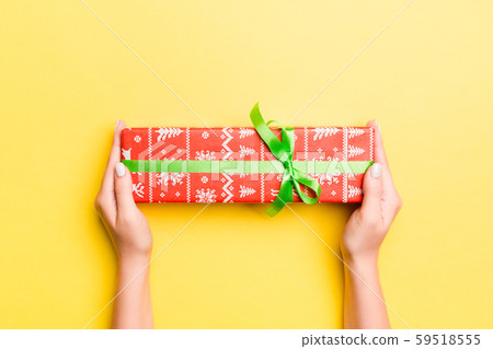 Woman arms holding gift box with colored ribbon on 59518555