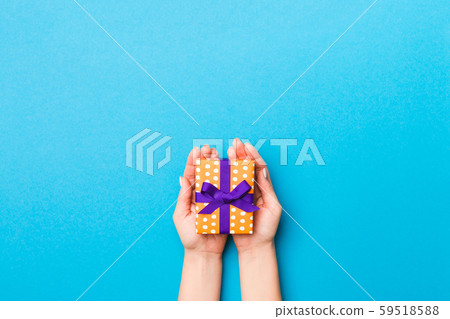 Woman arms holding gift box with colored ribbon on 59518588