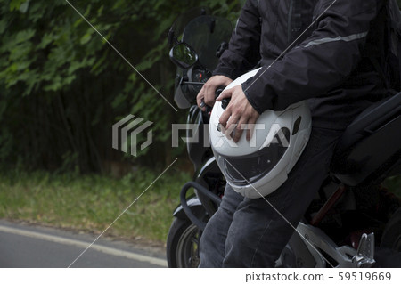 Driver riding motorcycle on an asphalt road through forest. 59519669