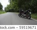 Driver riding motorcycle on an asphalt road through forest. 59519671