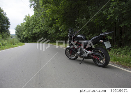 Driver riding motorcycle on an asphalt road through forest. Driver riding motorcycle on an asphalt road through forest. 59519671