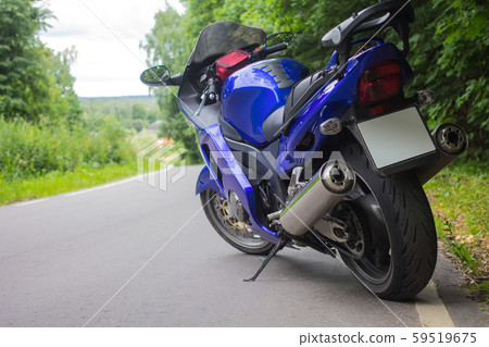 Driver riding motorcycle on an asphalt road through forest. 59519675
