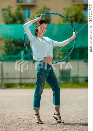 Stylish girl with a thin waist in jeans on a sports hoop 59521707