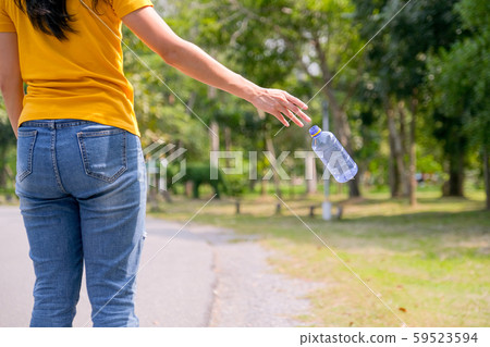 Yellow t-shirt woman is throwing plastic bottle on the road of garden or park 59523594