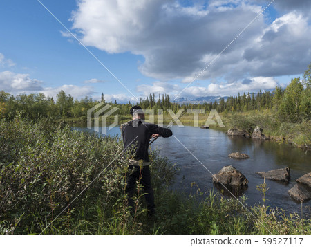 Fisherman man catching fish at beautiful northern landscape with azure blue river Kamajokk Fisherman man catching fish at beautiful northern landscape with azure blue river Kamajokk 59527117
