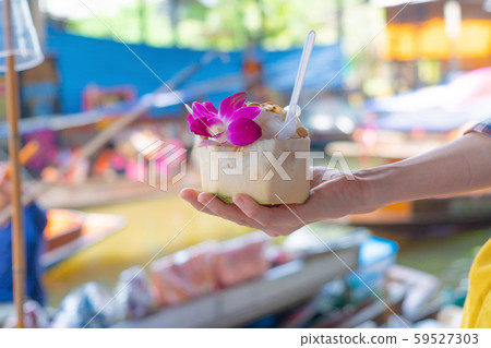 Asian woman eating coconut ice cream at Damnoen Asian woman eating coconut ice cream at Damnoen 59527303