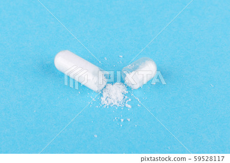 one open capsule of nutritional supplement msm, sulfur, on blue background 59528117