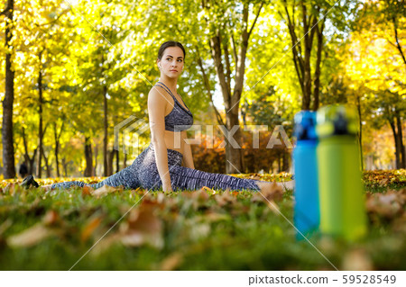 sporty woman stretching on green grass in park 59528549
