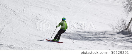 Skier downhill on snowy ski slope at sunny day Skier downhill on snowy ski slope at sunny day 59529291