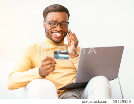 Carefree Guy Using Credit Card And Laptop Shopping Sitting Indoor Carefree Guy Using Credit Card And Laptop Shopping Sitting Indoor 59529569