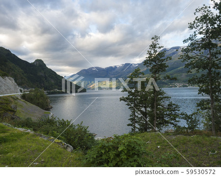 View over blue water of Hardanger Fjord in Kinsarvik in Norway with small village on the coast View over blue water of Hardanger Fjord in Kinsarvik in Norway with small village on the coast 59530572