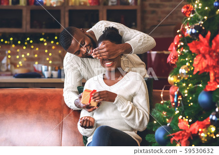 Loving black husband surprising his wife with Christmas gift. 59530632