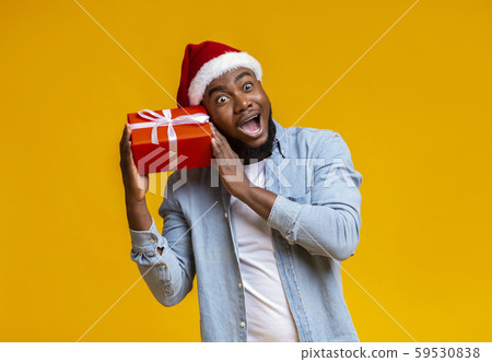 Crazy black guy in Santa hat holding Christmas gift box Crazy black guy in Santa hat holding Christmas gift box 59530838