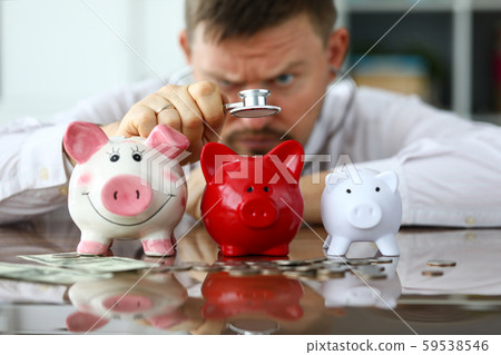 Hand of businessman with stethoscope examining three piggybanks 59538546