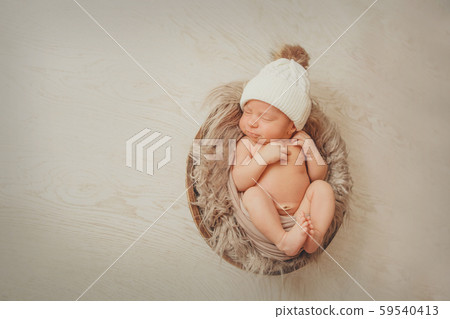 a newborn baby wrapped in a blanket with a warm hat on his head. the concept of childhood, health, IVF. a newborn baby wrapped in a blanket with a warm hat on his head. the concept of childhood, health, IVF. 59540413