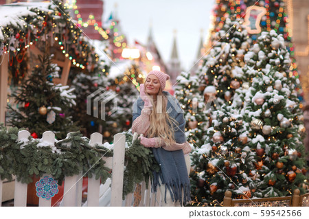 Close-up of a blonde in mittens and a scarf against the background of New Year's city trees Close-up of a blonde in mittens and a scarf against the background of New Year's city trees 59542566