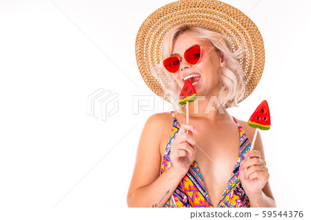 Happy blonde caucasian female stands in swimsuit with watermelon lolipops and smiles isolated on Happy blonde caucasian female stands in swimsuit with watermelon lolipops and smiles isolated on 59544376