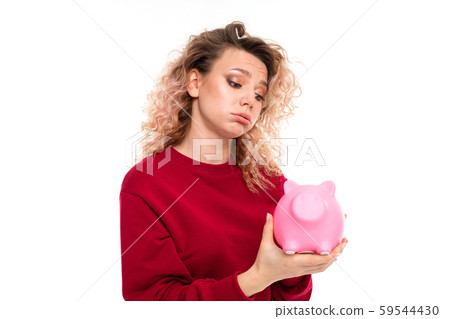Caucasian girl with curly fair hair holds a pink pig moneybox, portrait isolated on white background Caucasian girl with curly fair hair holds a pink pig moneybox, portrait isolated on white background 59544430