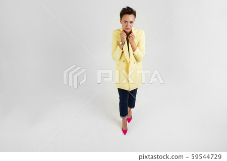 Woman in yellow autumn coat is cold 59544729