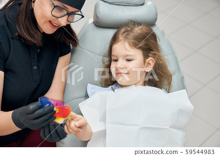Dentist and child looking at braces. 59544983
