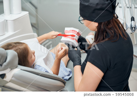 Doctor showing to little patient how to brush teeth. 59545008