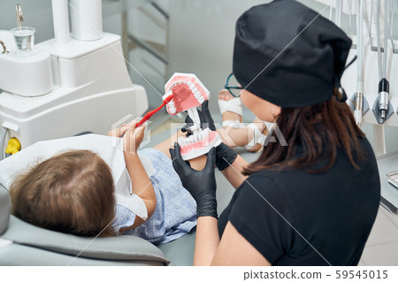 Girl teaching how to brush teeth on teeth model. 59545015