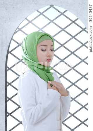 Asian Muslim woman in a veil standing and praying Asian Muslim woman in a veil standing and praying 59545487