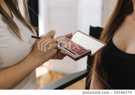 Makeup artist hold a pelette and put brush for work 59546374