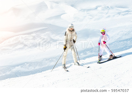 Young adult beautiful sporty mother having fun skiing with kid daughter on mountain alpine ski 59547037