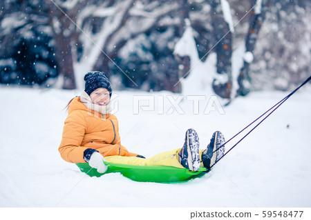 Adorable little happy girl sledding in winter snowy day. Adorable little happy girl sledding in winter snowy day. 59548477