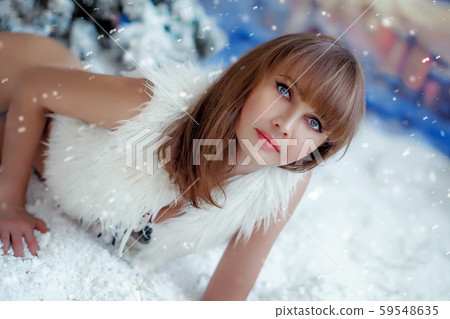 Close-up of a model in a photo studio near a Christmas tree with artificial snow Close-up of a model in a photo studio near a Christmas tree with artificial snow 59548635