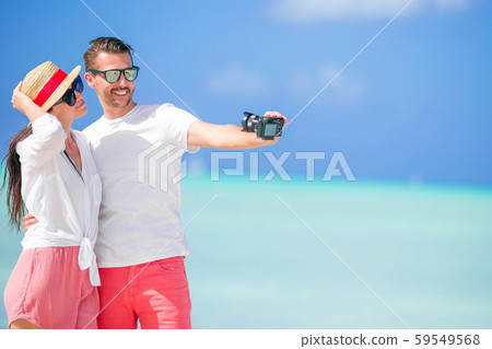Happy couple taking a selfie photo on white beach. Two adults enjoying their vacation on tropical 59549568