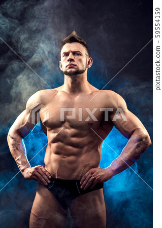 Handsome power athletic man bodybuilder. Fitness muscular body on dark smoke background. Perfect 59554159