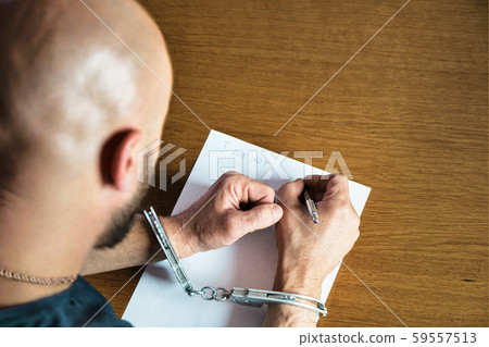 Men hands with handcuffs fill the police record, confession. on top of the police investigative 59557513