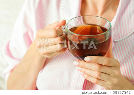 Young woman relaxing on sofa holding cup with lemon tea. Woman dreaming in living room lying on Young woman relaxing on sofa holding cup with lemon tea. Woman dreaming in living room lying on 59557542