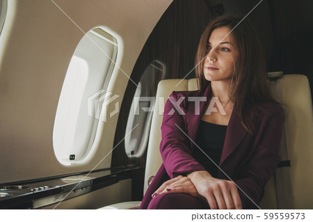 beautiful young woman sits in a plane near the window beautiful young woman sits in a plane near the window 59559573
