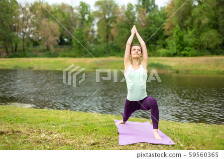 A young sports girl practices yoga on a green lawn A young sports girl practices yoga on a green lawn 59560365