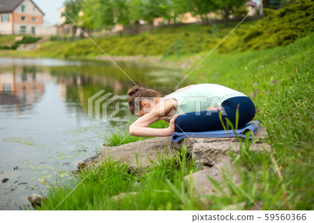 A young sports girl practices yoga on a green lawn A young sports girl practices yoga on a green lawn 59560366